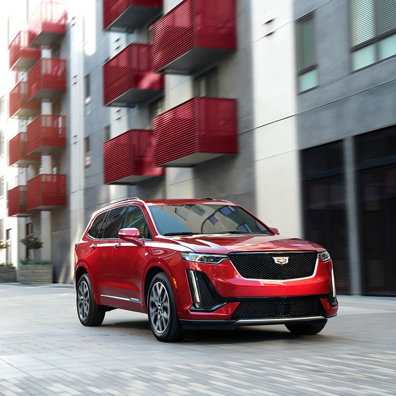 VUS intermédiaire à 7 places Cadillac XT6 2023 stationné devant un bâtiment.