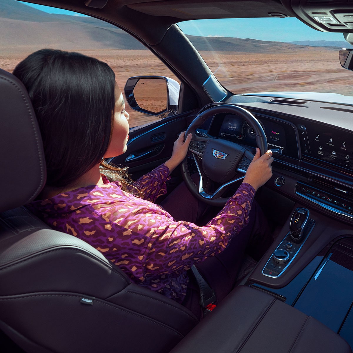 A person with hands on the steering wheel inside the 2024 Cadillac Escalade.