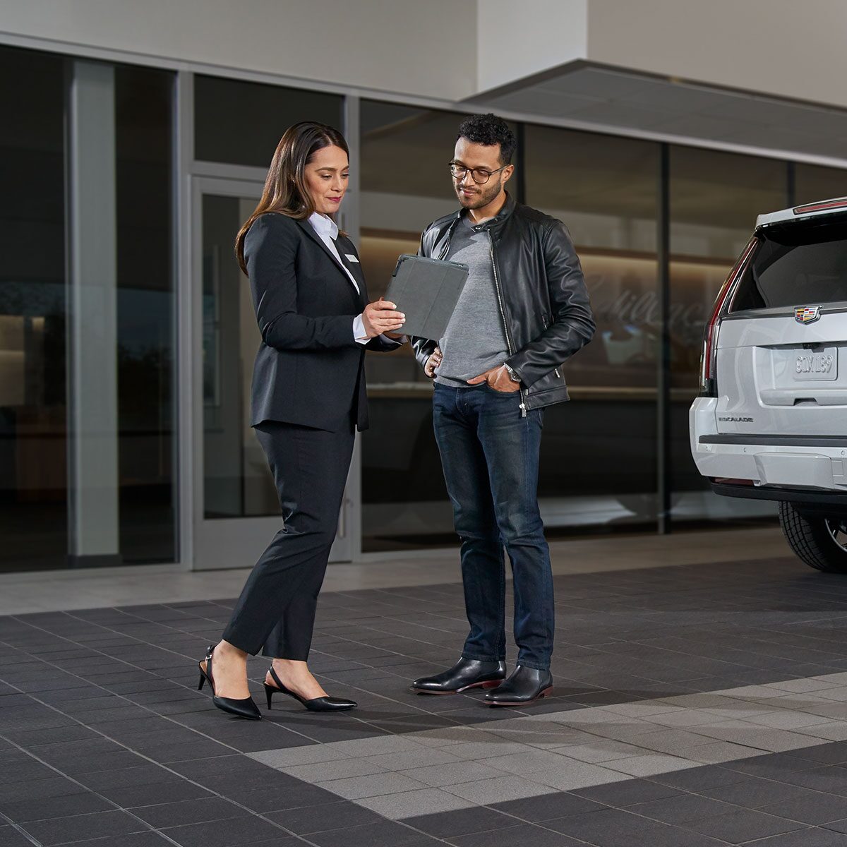 A person talking to a Cadillac tour agent outside a modern building.