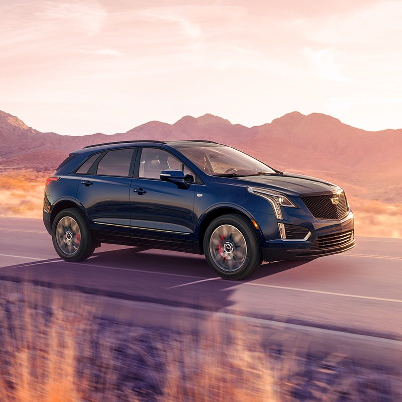 Le Cadillac XT5 2024 en mouvement sur l’autoroute devant des montagnes.