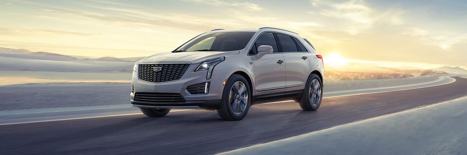 The 2024 Cadillac XT5 speeding down a highway at sunrise.