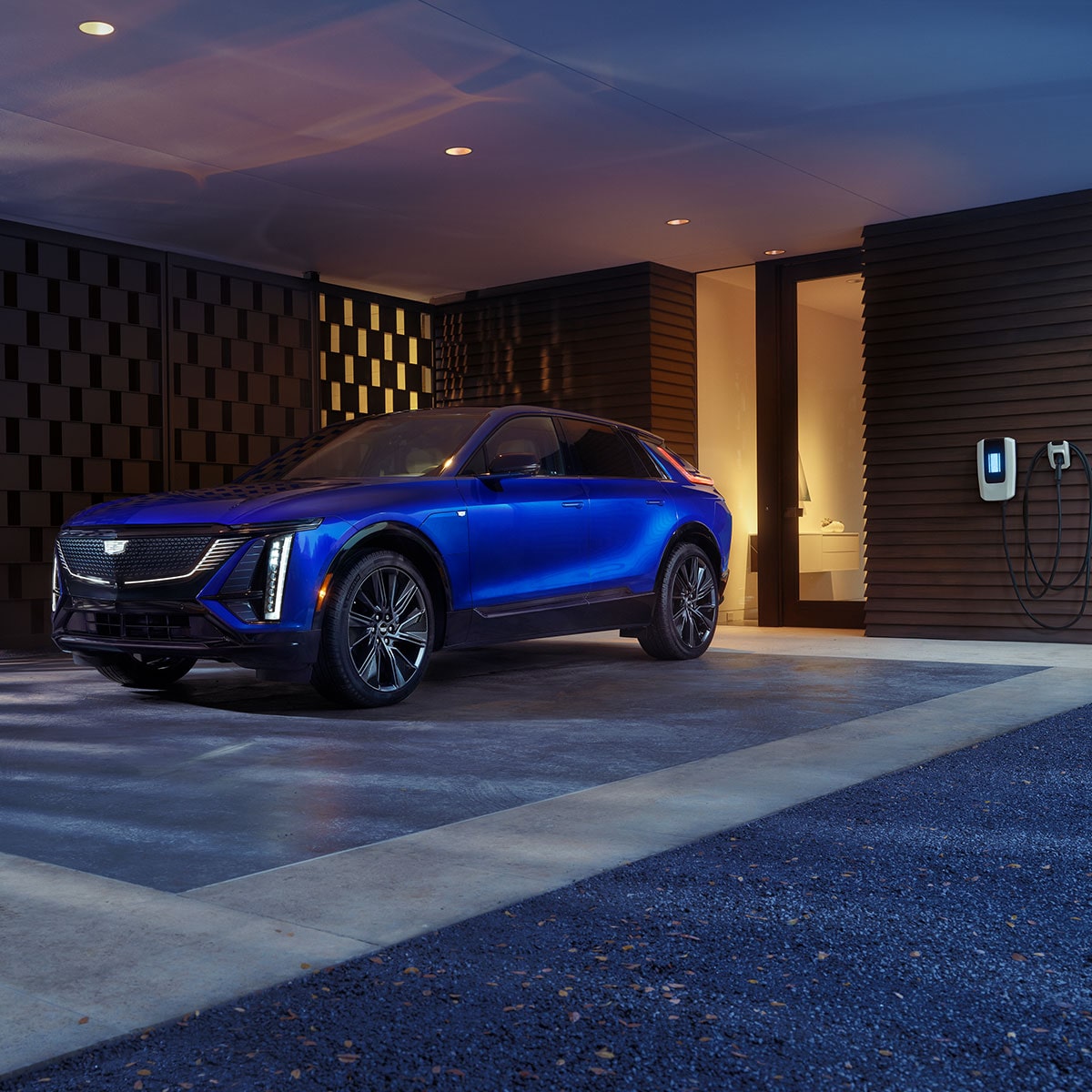 Cadillac LYRIQ 2025 stationnée dans une allée de maison pendant qu'elle est en recharge EV.