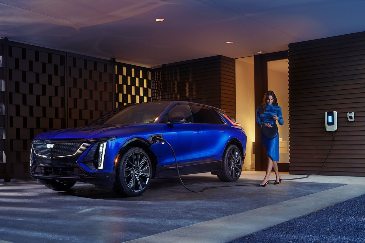 2025 Cadillac LYRIQ charging at home as a person passes by.