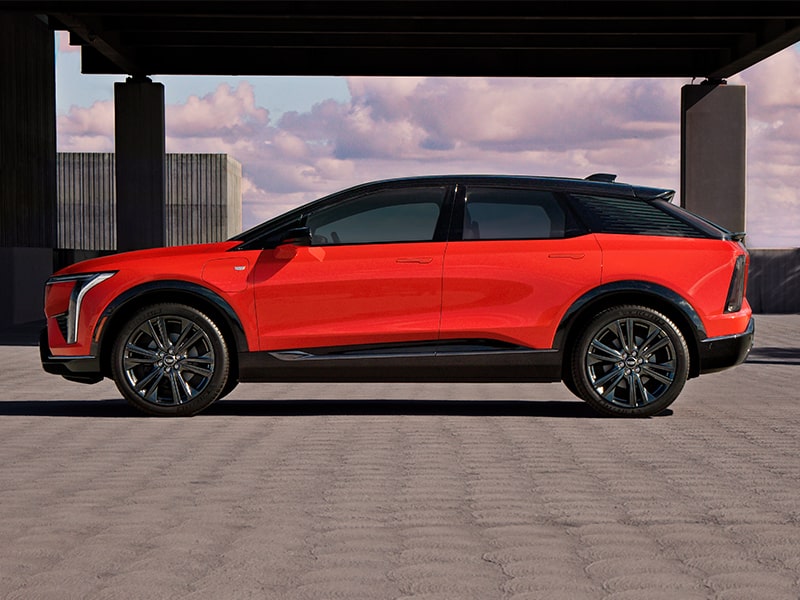 Vue latérale du VUS électrique Cadillac OPTIQ 2025 stationné devant une structure.