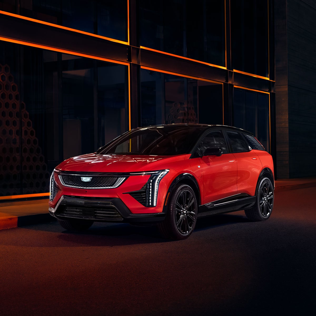 2025 Cadillac OPTIQ electric SUV parked in a brightly lit area at night.