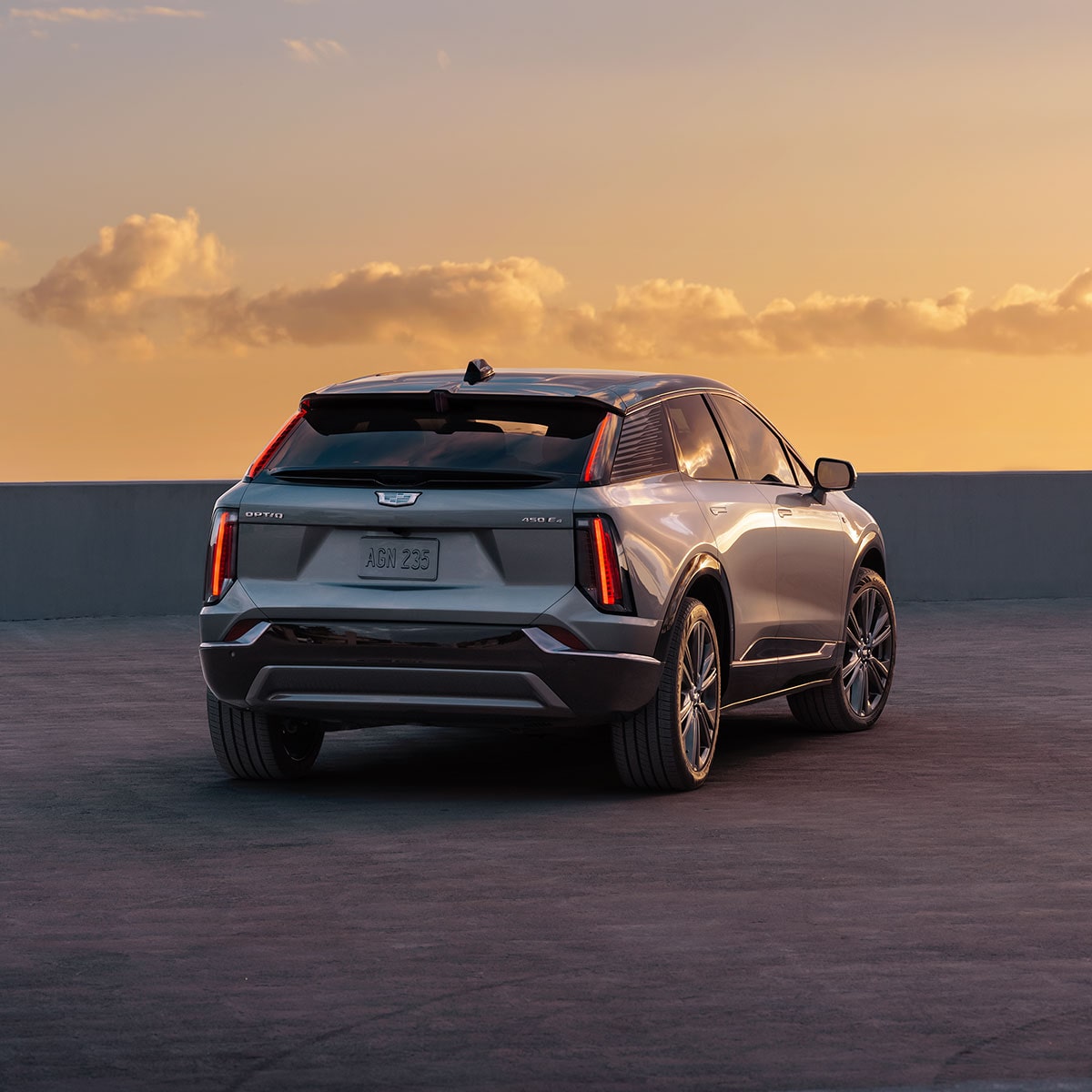 Back view of the 2025 Cadillac OPTIQ electric SUV parked alone during sunset.