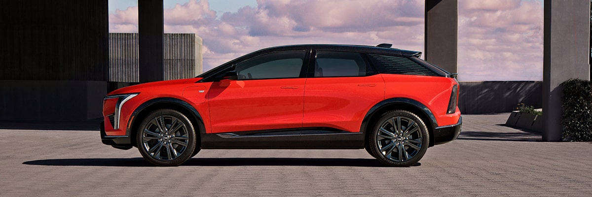Vue latérale du VUS électrique Cadillac OPTIQ 2025 stationné devant une structure.