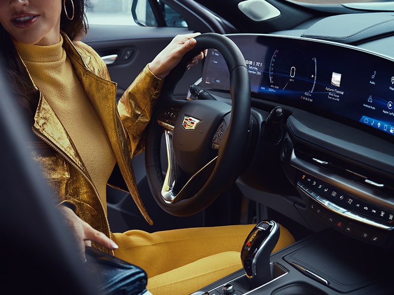 A person holding the steering wheel while looking back inside the 2025 Cadillac XT4.