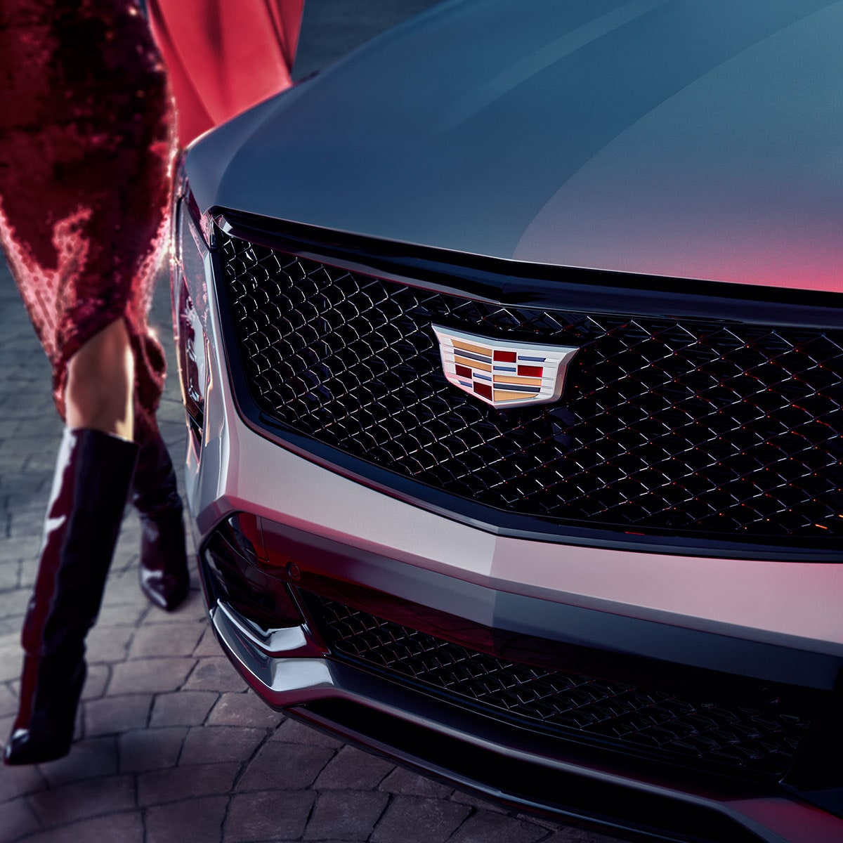 Vue latérale avant de la calandre du Cadillac XT4 2025 avec une personne qui passe à côté.