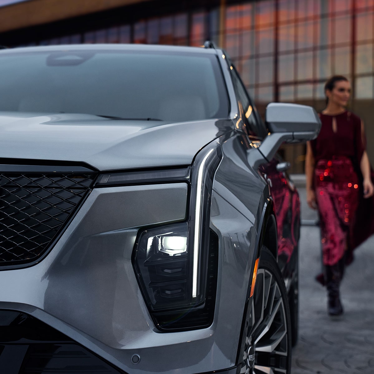 Vue avant du Cadillac XT4 2025 avec les phares allumés pendant qu’une personne passe en arrière-plan.