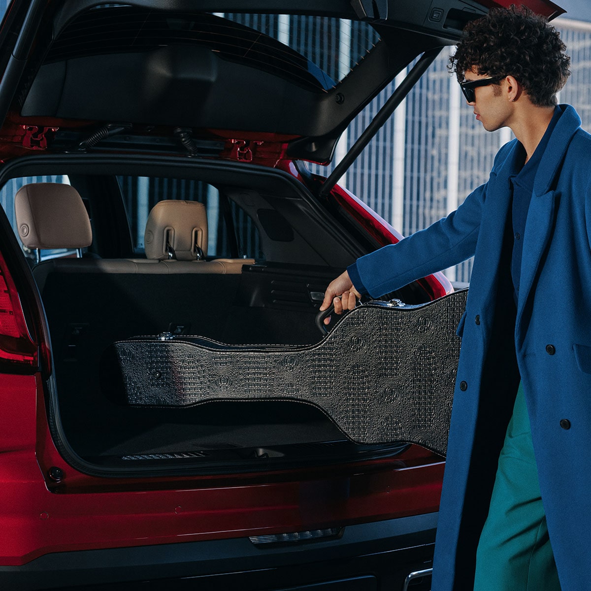 Une personne range des objets dans le grand espace utilitaire du Cadillac XT4 2025.