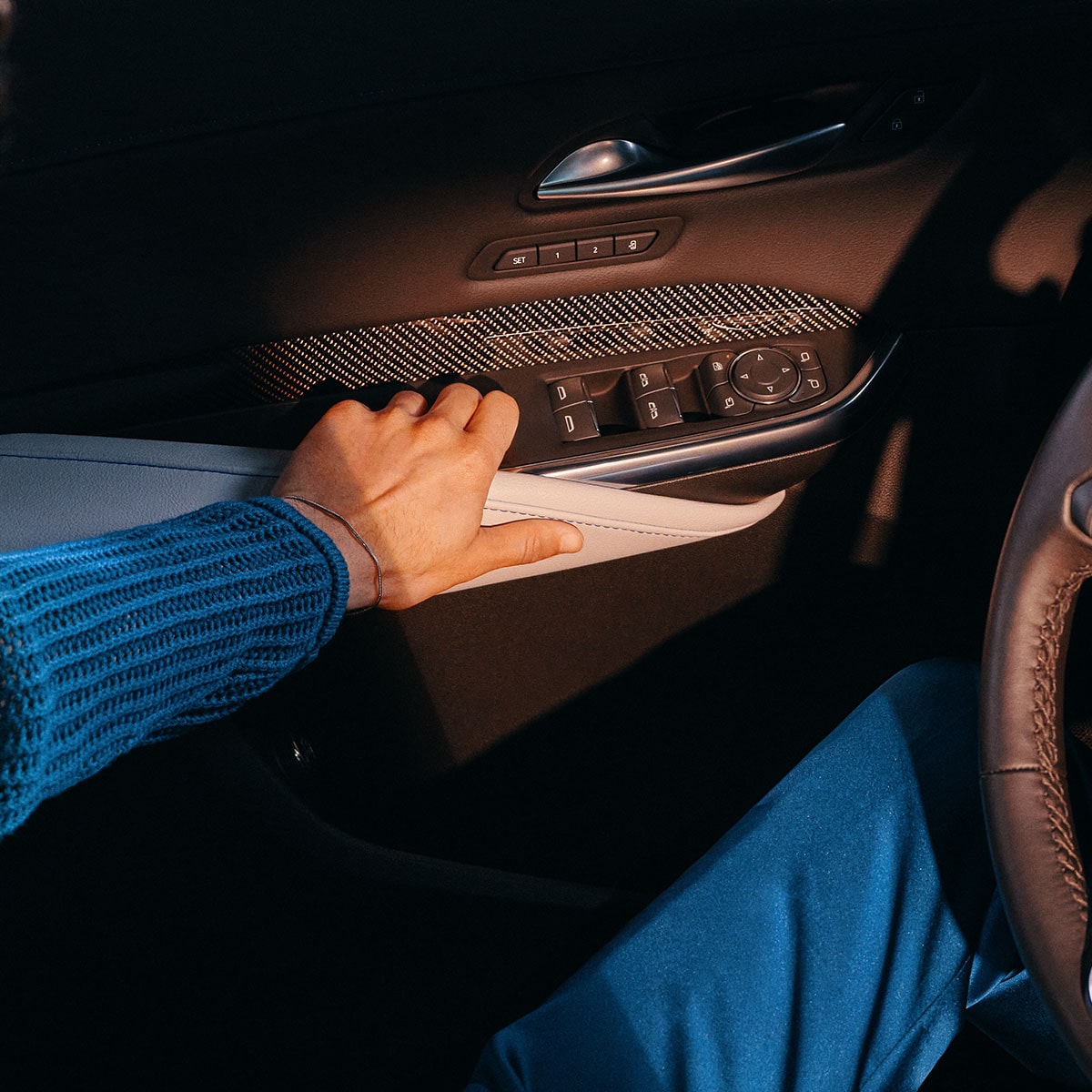 Une personne assise dans le Cadillac XT4 2025 met la main sur la poignée de la porte.