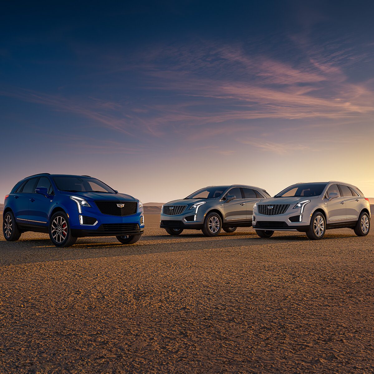 Trois VUS de luxe Cadillac XT5 2025 stationnés à l’extérieur au lever du soleil.