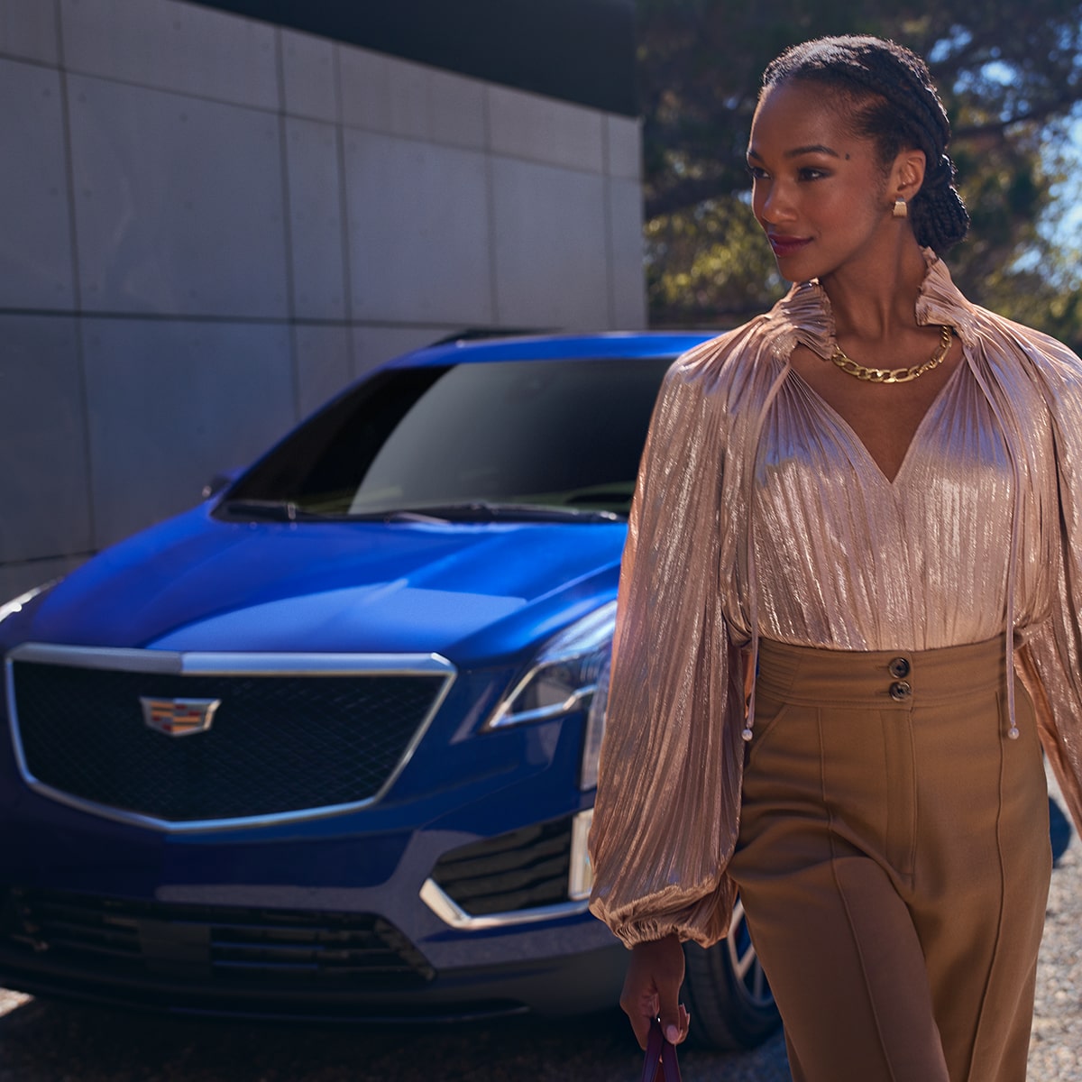 Une personne passe à côté d’un VUS de luxe Cadillac XT5 2025 stationné devant un mur.