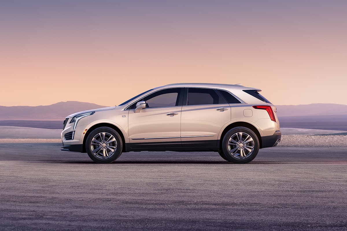 Vue latérale du VUS de luxe Cadillac XT5 2025 stationné à l’extérieur au lever du soleil.