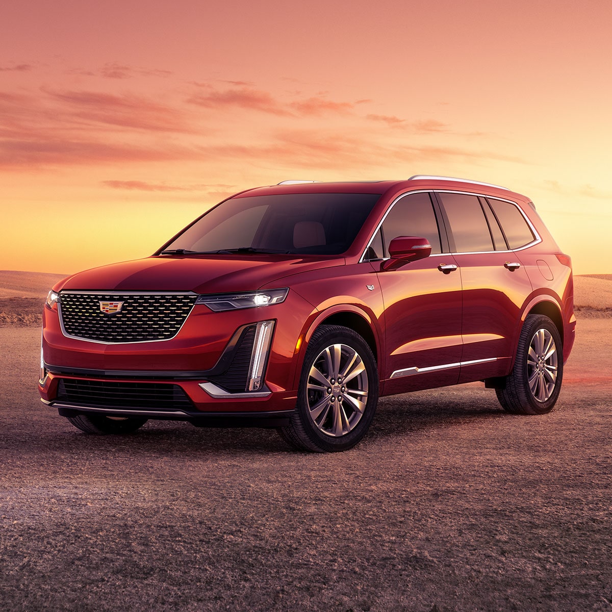 Vue latérale avant du VUS intermédiaire 7 passagers Cadillac XT6 2025 stationné à l’extérieur au coucher du soleil.