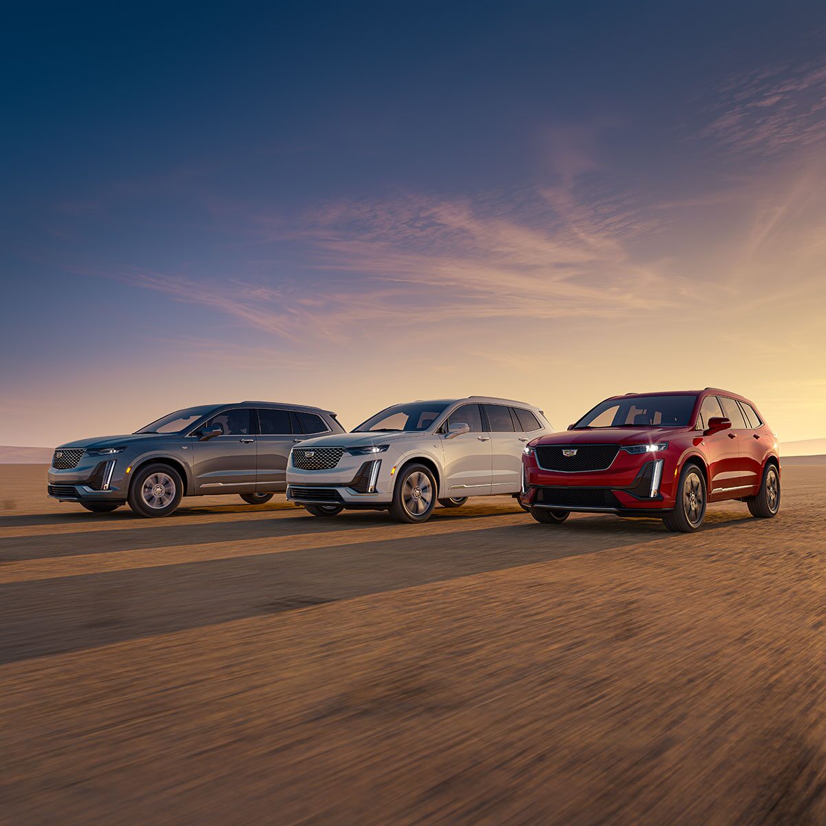 Trois VUS intermédiaires 7 passagers Cadillac XT6 2025 stationnés les uns à côté des autres à l’extérieur.