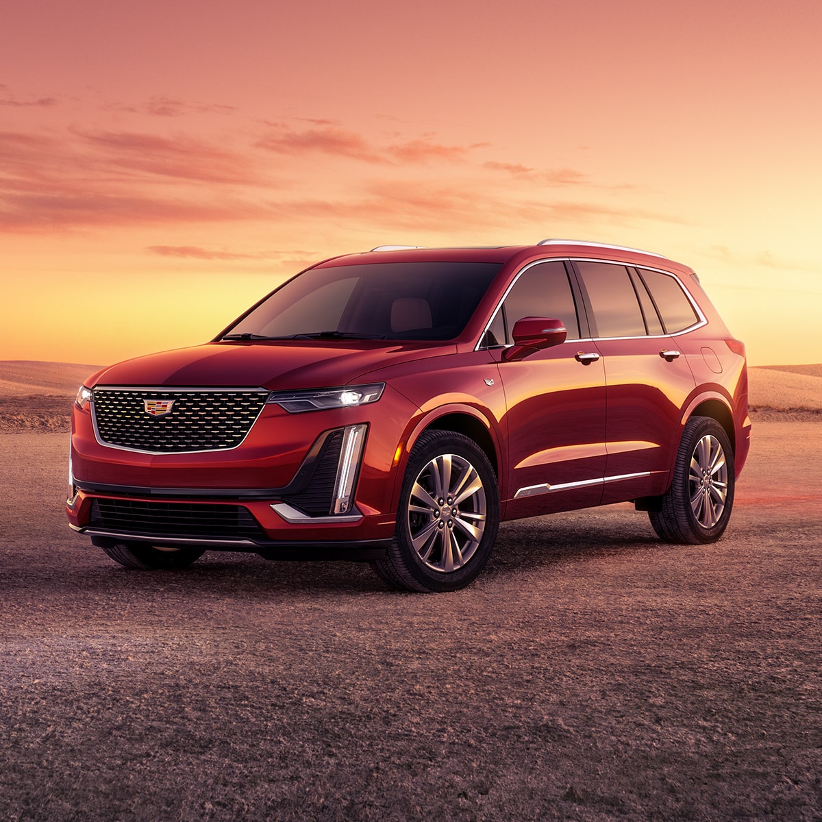 Vue latérale avant du VUS intermédiaire 7 passagers Cadillac XT6 2025 stationné à l’extérieur au coucher du soleil.