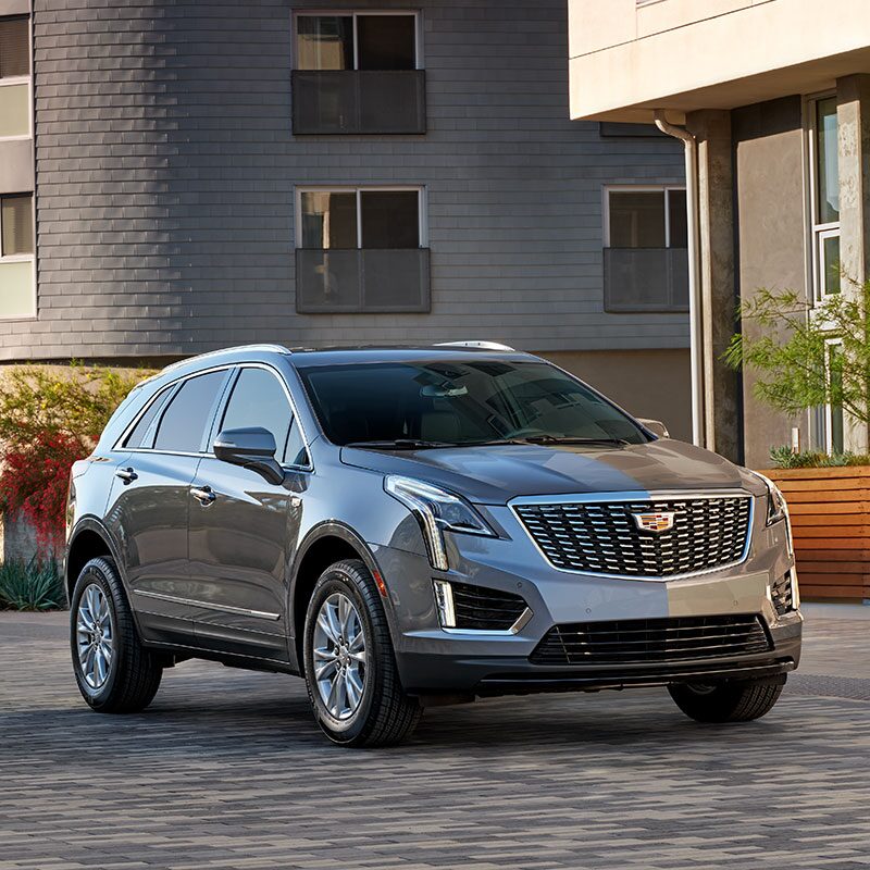 Right profile view of the 2023 Cadillac XT5 parked outside a home.