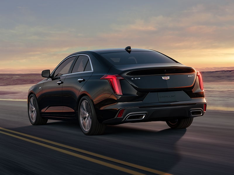 Vue latérale arrière de la berline de luxe Cadillac CT4 2025 en mouvement seule sur une route à flanc de colline.