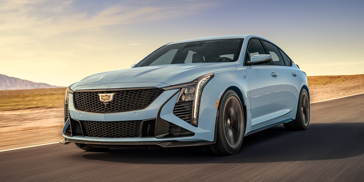 Vue latérale avant de la Cadillac CT5-V 2025 en mouvement sur une route aride.
