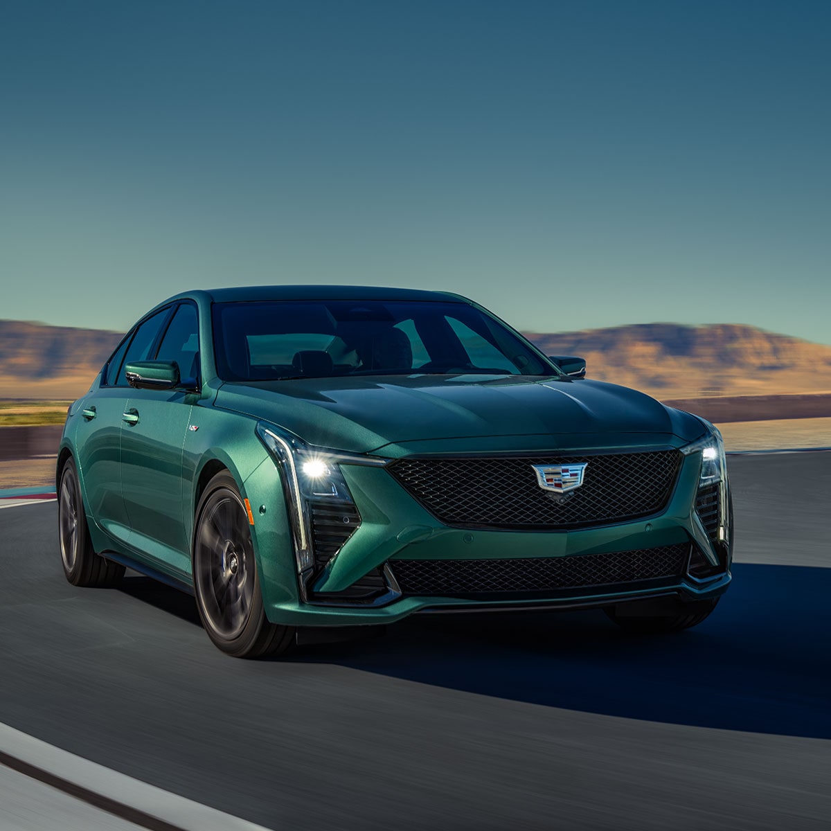 Vue latérale avant de la Cadillac CT5-V 2025 en mouvement seule sur une route aride.