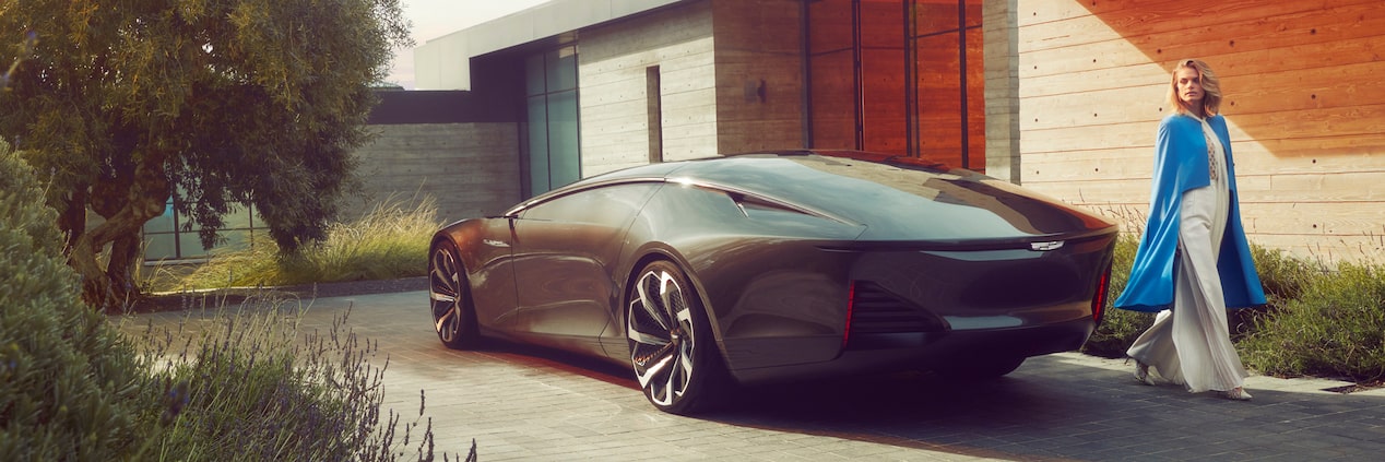 A Cadillac InnerSpace Concept Vehicle parked outside a modern home as a person walks by.
