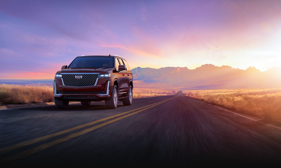 2023 Cadillac Escalade driving during a sunset.