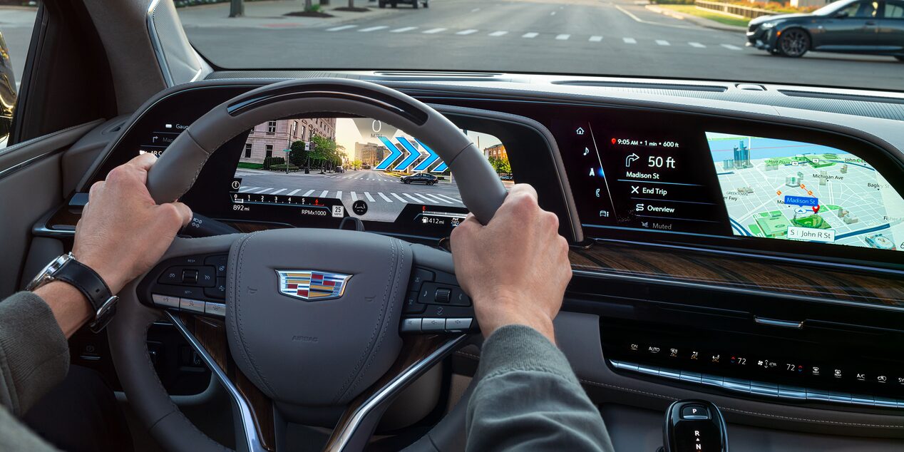 A person holding the steering wheel of the 2023 Cadillac Escalade featuring the augmented reality navigation.
