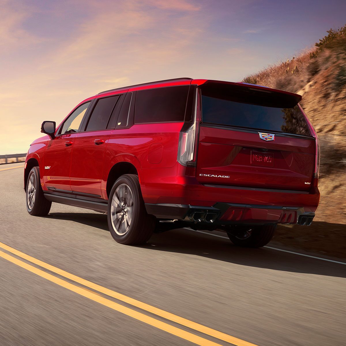 Back view of the 2024 Cadillac Escalade-V parked on a pavement with hills in the background.