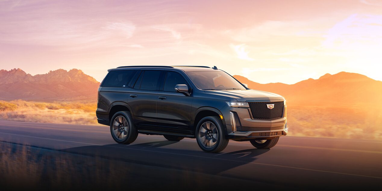 2024 Cadillac Escalade parked on a pavement with large rocks in the background.