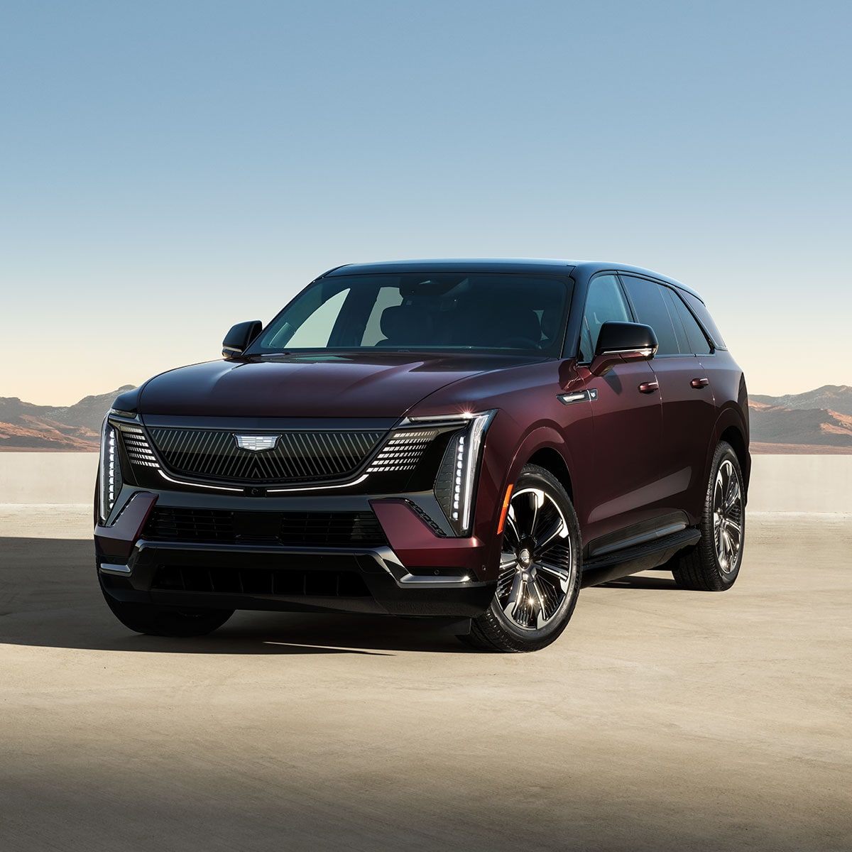 Front three quarter view of a Cadillac Escalade IQ electric SUV parked alone in an arid terrain.