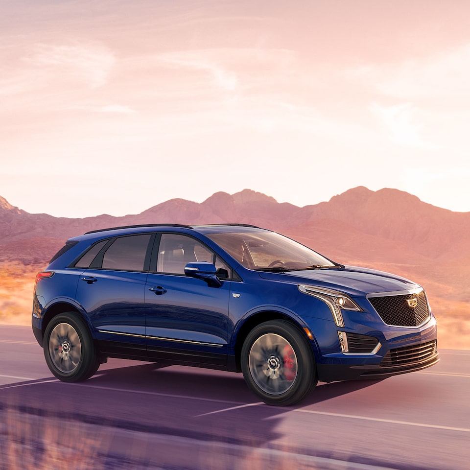 2026 Cadillac XT5 luxury SUV driving alone on a countryside road.