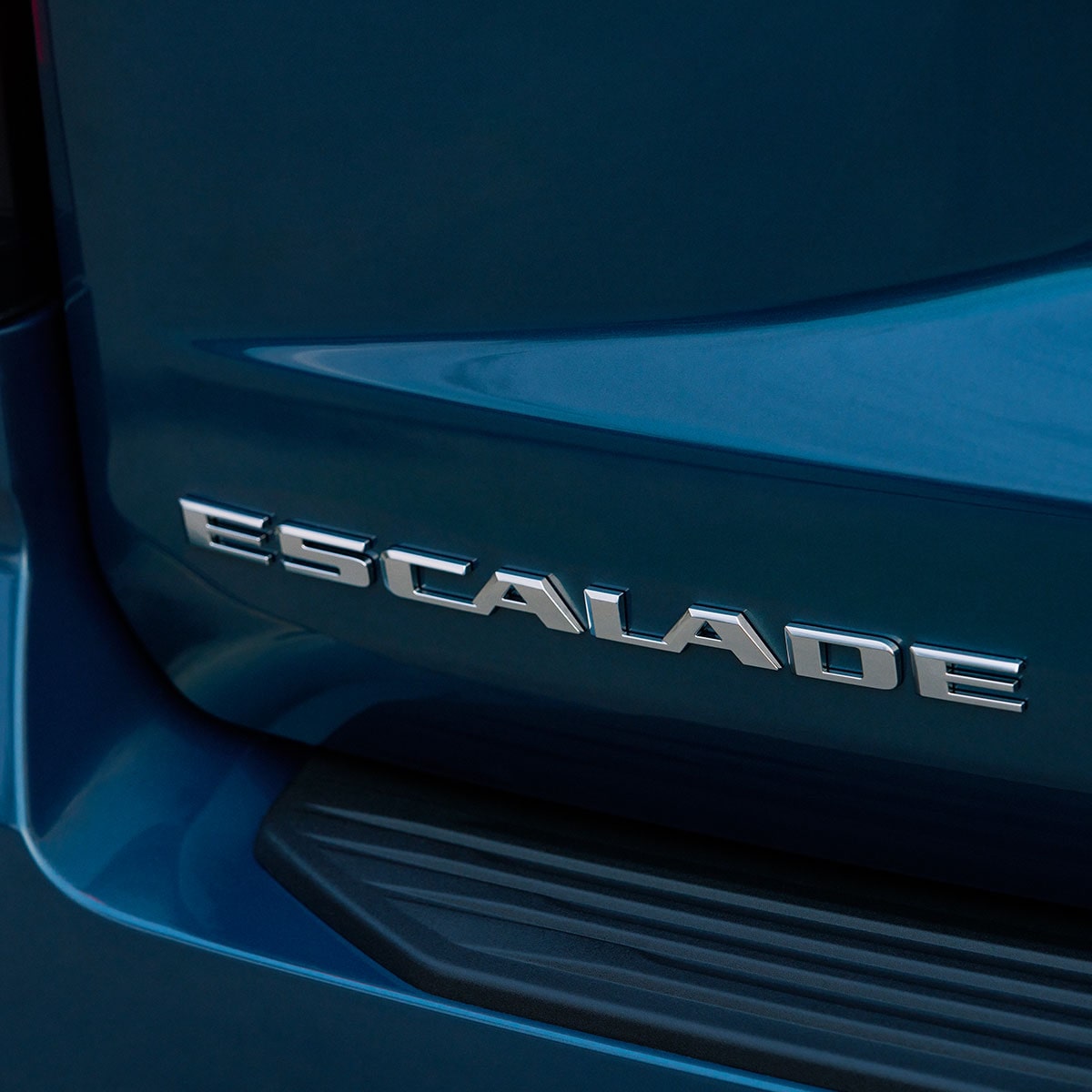 Vue rapprochée de l’inscription Cadillac Escalade chromée sur un hayon arrière bleu foncé