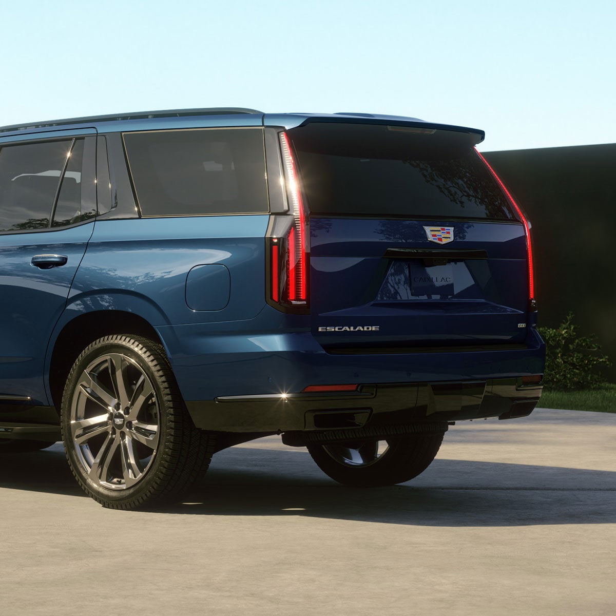 Un Cadillac Escalade 2027 bleu stationné dans l’entrée d’une résidence moderne en plein jour