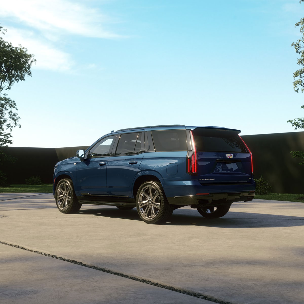 Un Cadillac Escalade 2027 bleu stationné dans l’entrée d’une résidence moderne en plein jour