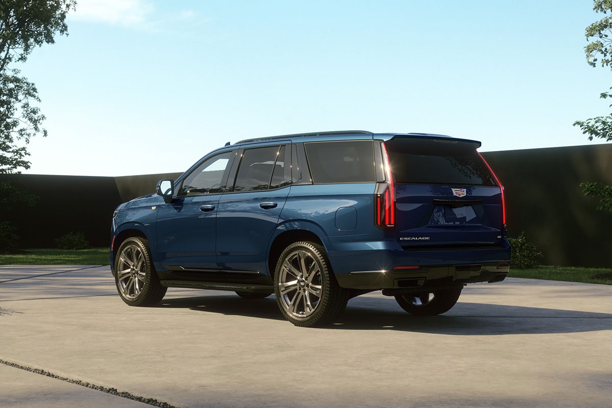 Une Cadillac Escalade bleue de 2027 garée dans l'allée d'une résidence moderne, en plein jour