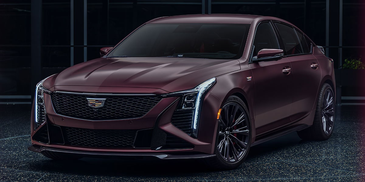 Vue latérale avant de la Cadillac CT5-V Blackwing stationnée dans un endroit peu éclairé.