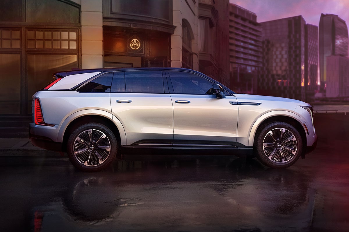 Side view of the 2025 Cadillac Escalade IQ electric suv driving alone in the city during a cloudy day.
