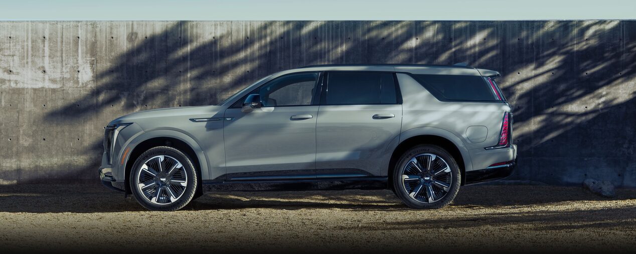 Vue latérale du Cadillac Escalade IQL 2026 stationné devant un mur.
