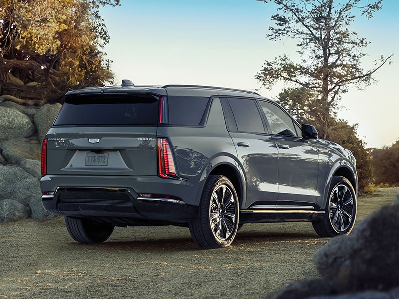 Vue latérale arrière du Cadillac Escalade IQL 2026 stationné à l’extérieur par une journée ensoleillée.