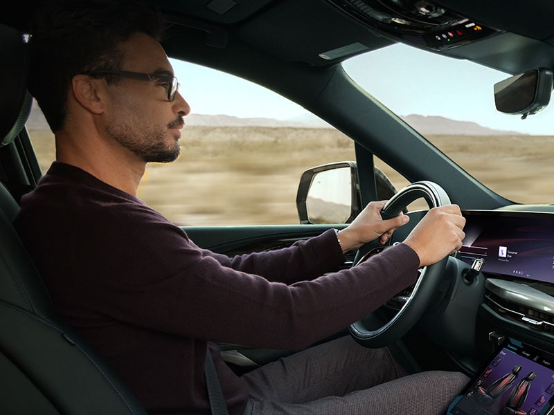 Vue latérale d’une personne qui tient le volant du Cadillac Escalade IQL 2026.