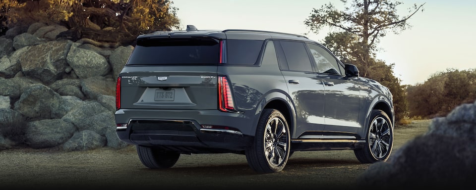 Vue latérale arrière du Cadillac Escalade IQL 2026 en mouvement dans un parc.