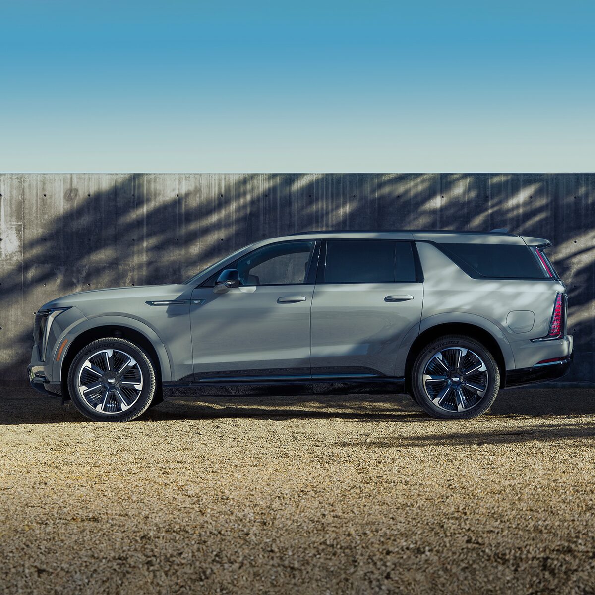 Vue latérale du Cadillac Escalade IQL 2026 stationné seul à l’extérieur par une journée ensoleillée.