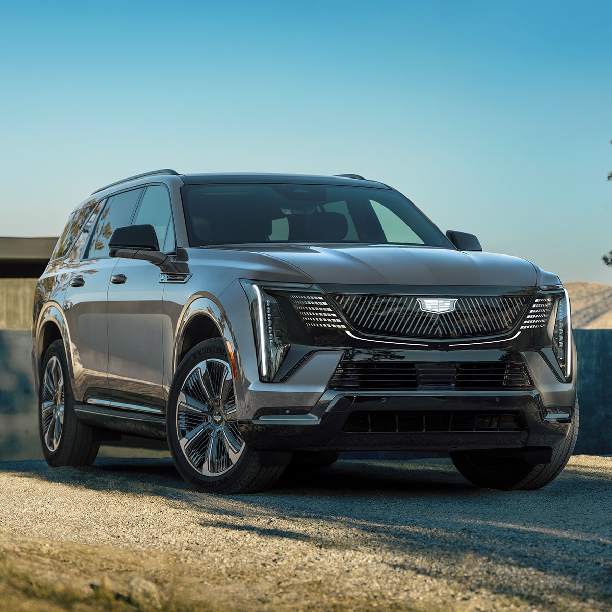 Vue latérale avant du Cadillac Escalade IQL 2026 stationné devant une maison.