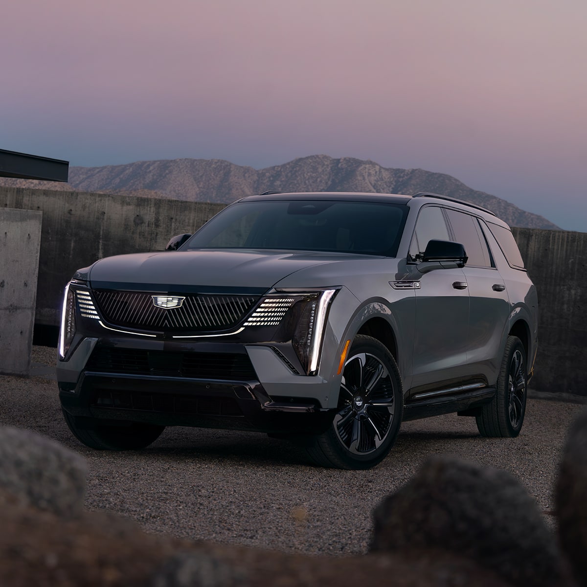 Vue latérale avant du Cadillac Escalade IQL 2026 stationné seul en soirée.