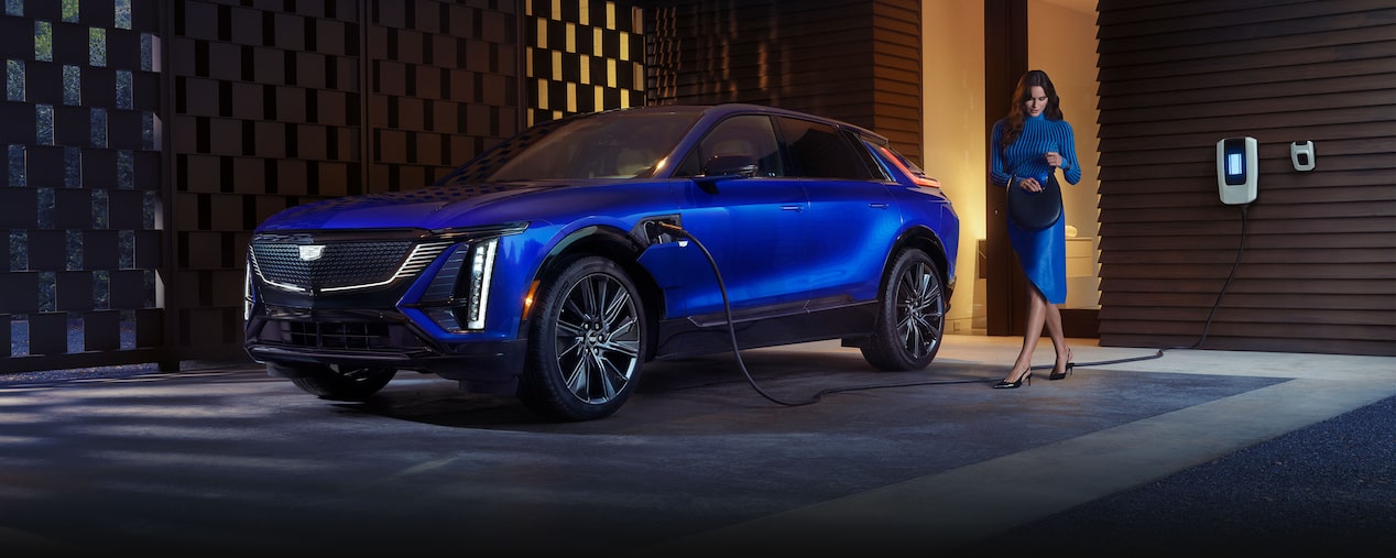 2026 Cadilac LYRIQ EV charging at home as a person passes by.