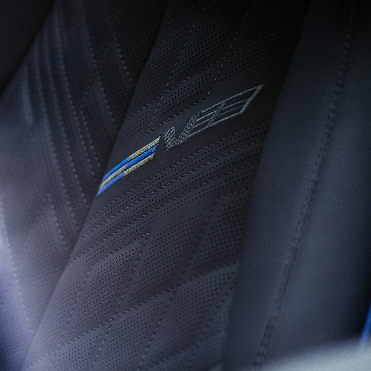 Close-up of V-Series embossed leather sport seat with blue stitching.