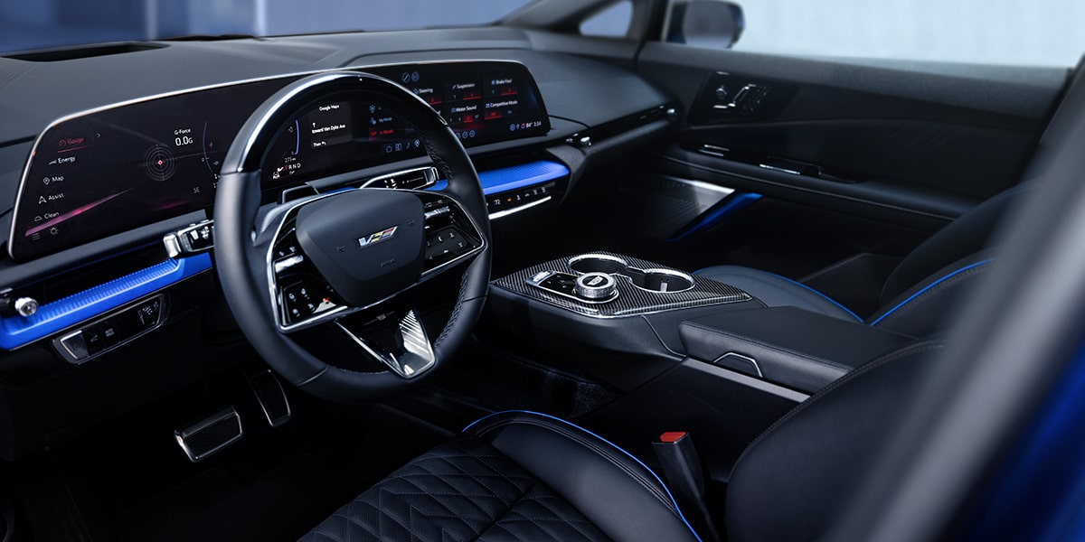 Interior shot showcasing the OPTIQ-V digital cockpit, steering wheel, and front seats.