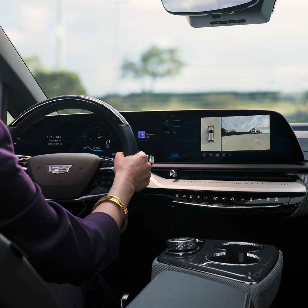 A driver holding the steering wheel of the 2026 Cadillac OPTIQ.